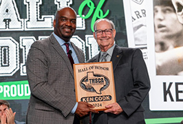  Two men stand together holding a plaque